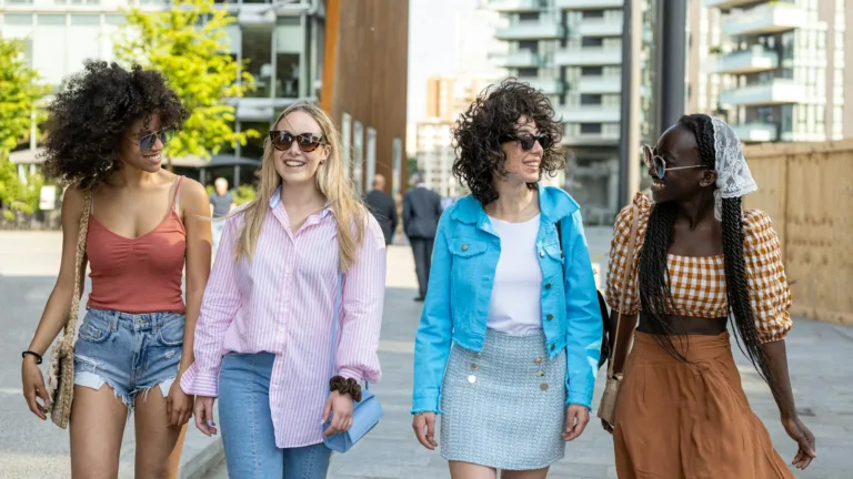 Four girls teenagers of Generation Z in the city, young women having fun walking in the city